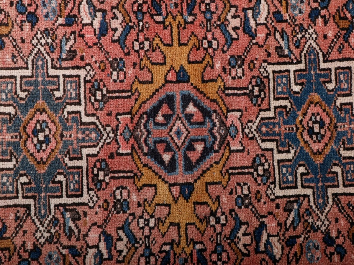 Close-up of Persian rug weave with coral, navy, and cream geometric motifs