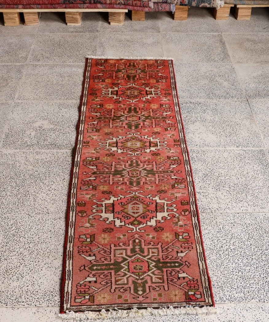 Persian Karaja runner rug on floor, red with repeating geometric border and central motifs
