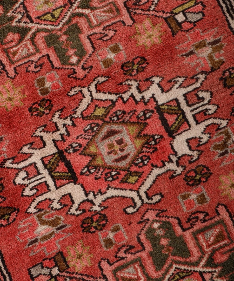 Close-up of Persian Karaja runner rug pattern in red with black, cream, and green accents