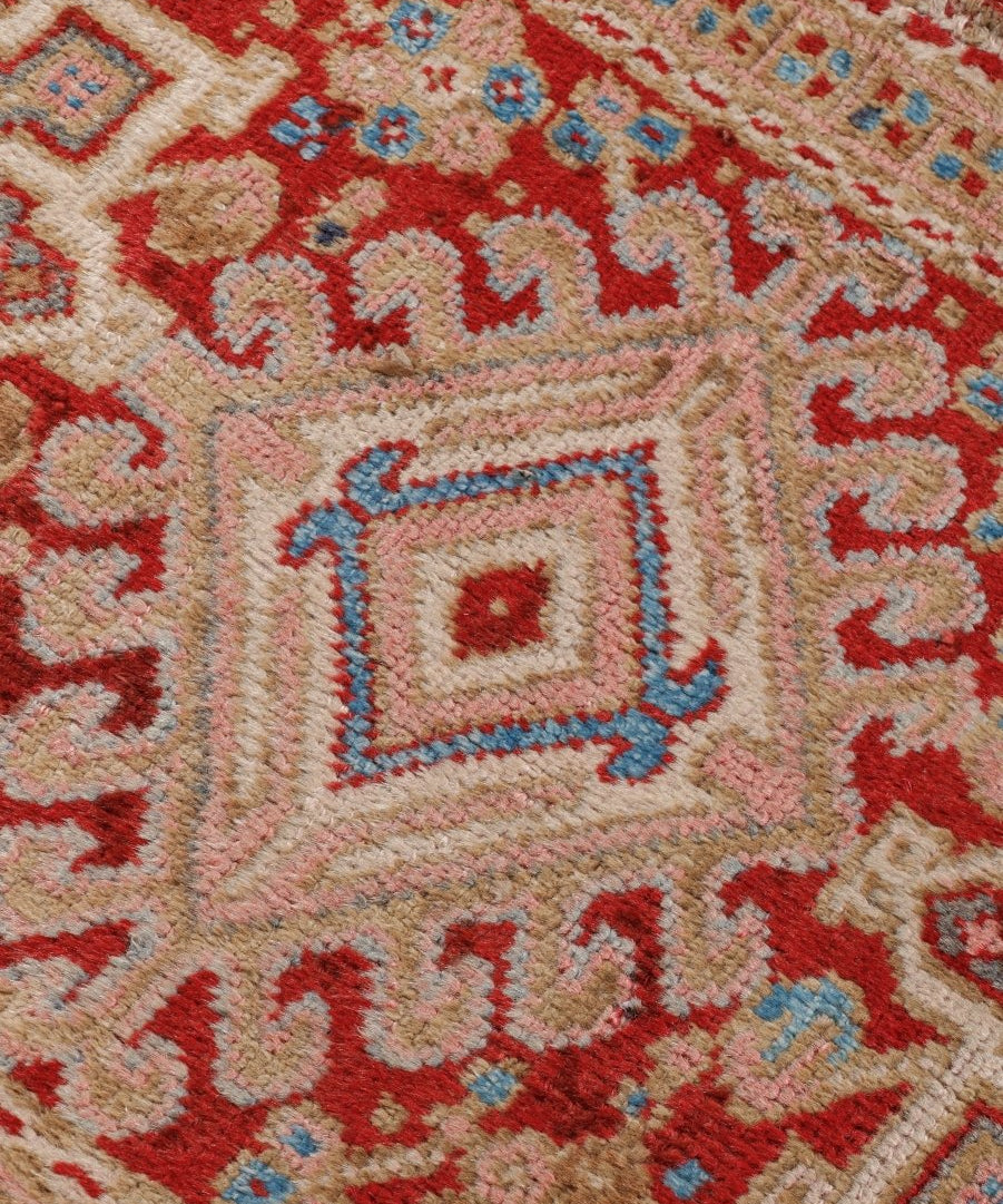 Close-up of Persian-style runner rug pattern with red, cream, and blue diamond motifs