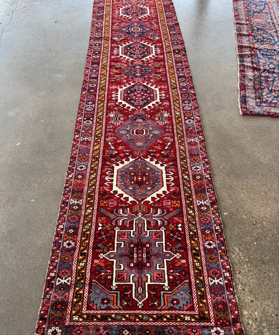 Narrow runner rug with repeating geometric designs in burgundy, navy, cream, and gold.