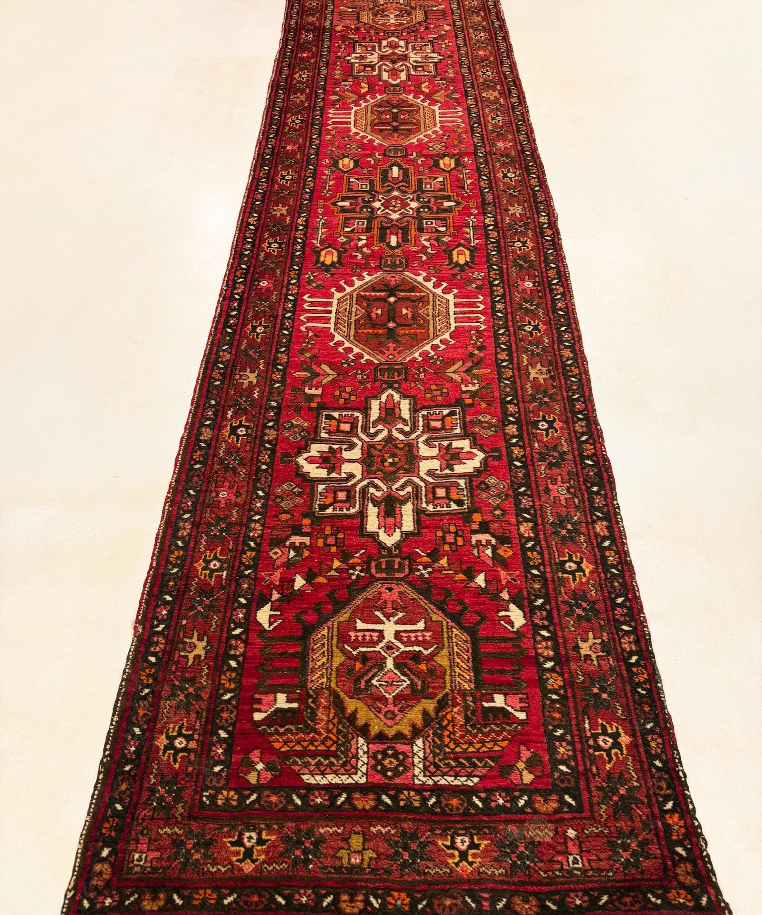 Red Persian-style runner rug with geometric medallion and ornate border