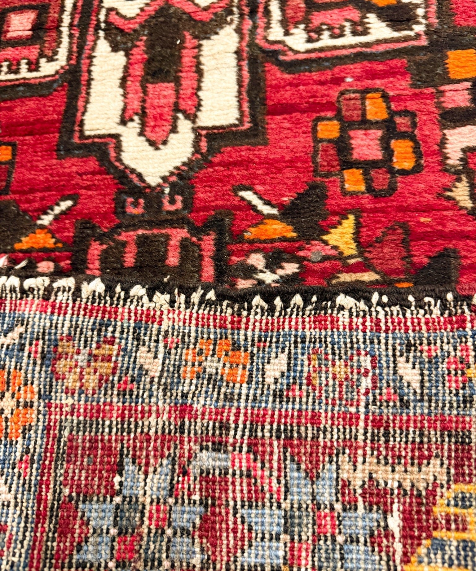 Close-up of red runner rug weave with multicolor geometric motifs and border