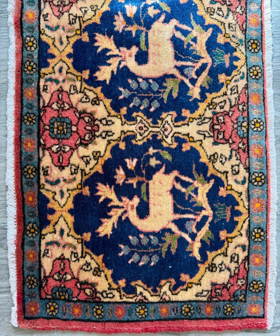 Persian Kashan rug with navy blue medallion and pink floral border, close-up corner