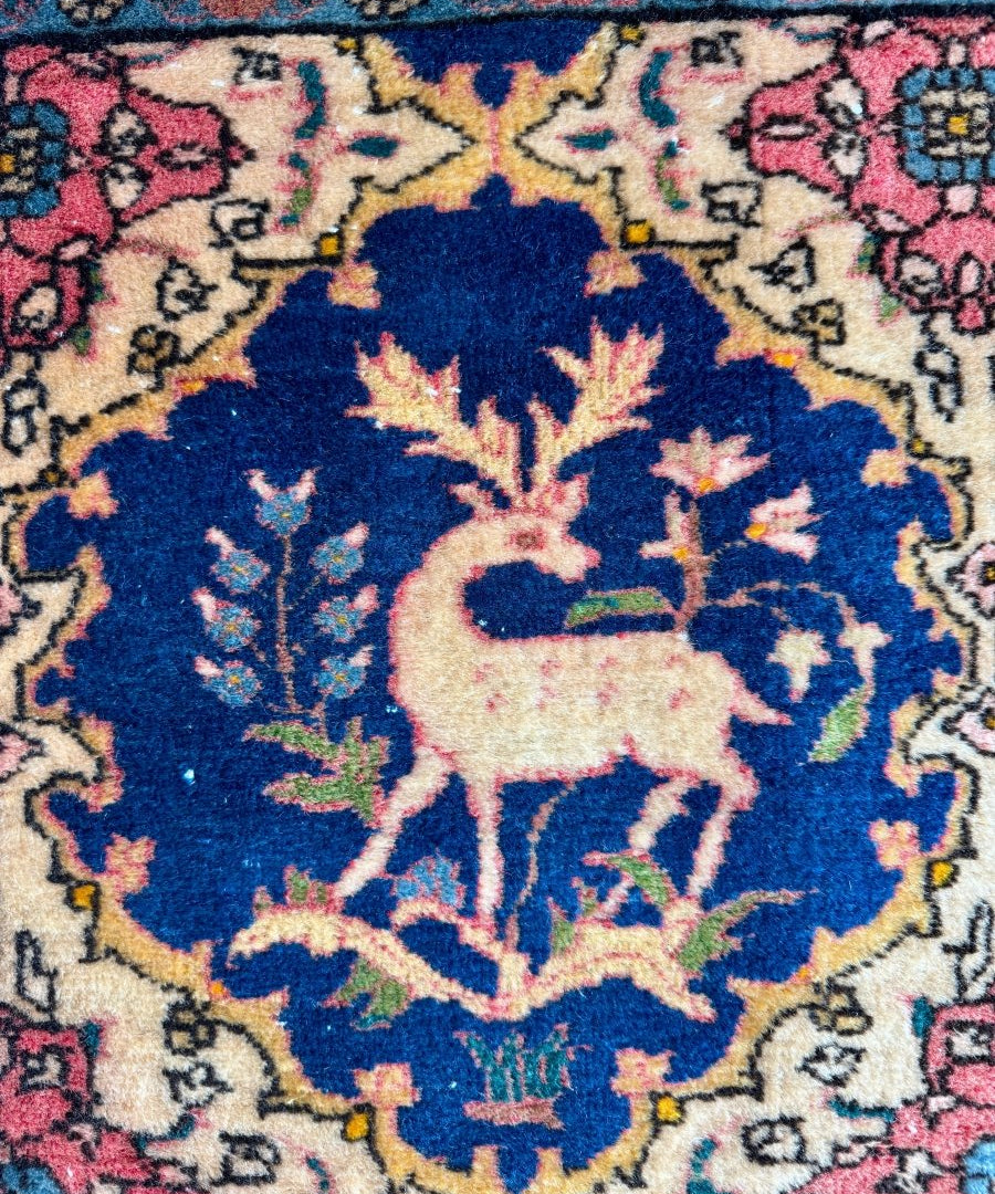 Persian Kashan rug medallion close-up with navy blue floral design and deer motifs