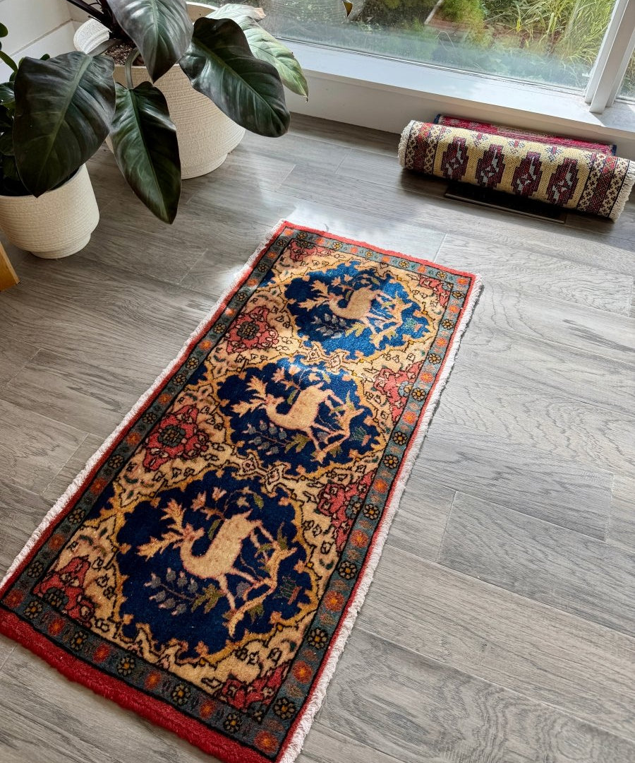 Persian Kashan rug with navy center medallions and red border, laid on light gray floor