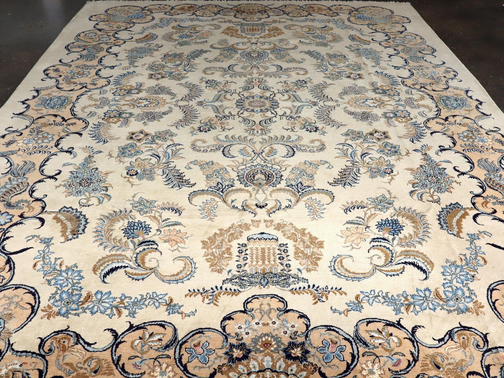 Persian Kashan rug with ivory field and blue floral medallion; ornate scrolling border