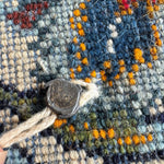 Persian Kashan rug texture detail with blue yarn loops, orange accents, and light fringe