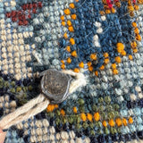 Persian Kashan rug texture detail with blue yarn loops, orange accents, and light fringe