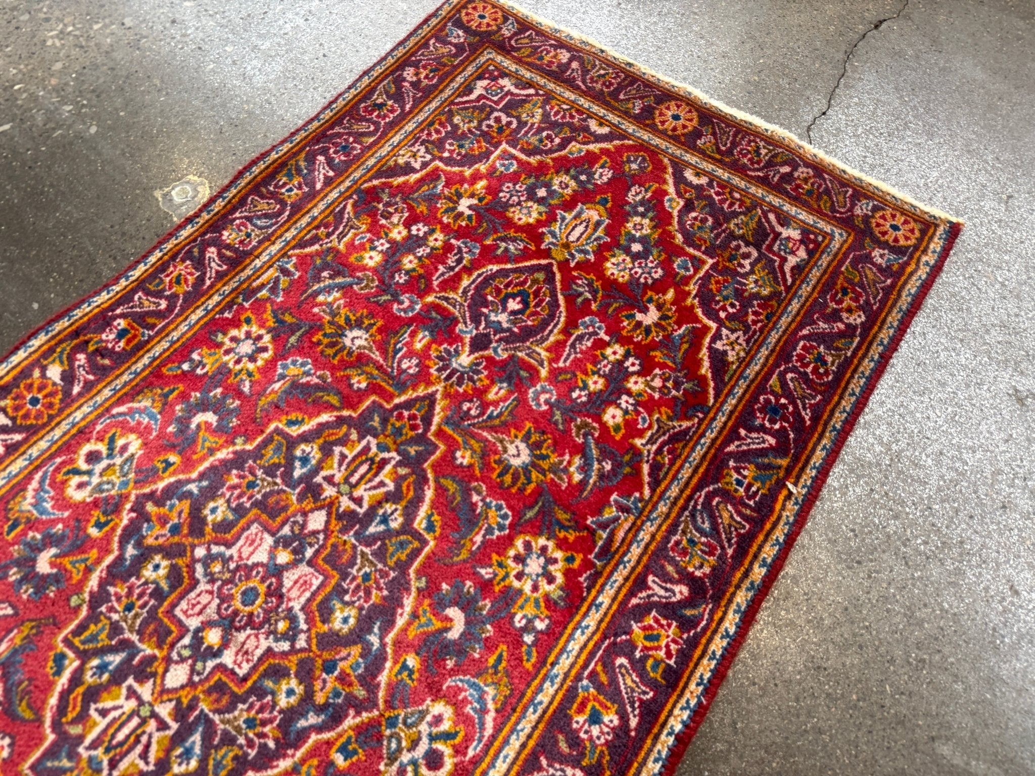Persian Kashan rug full view with red center medallion and navy floral border