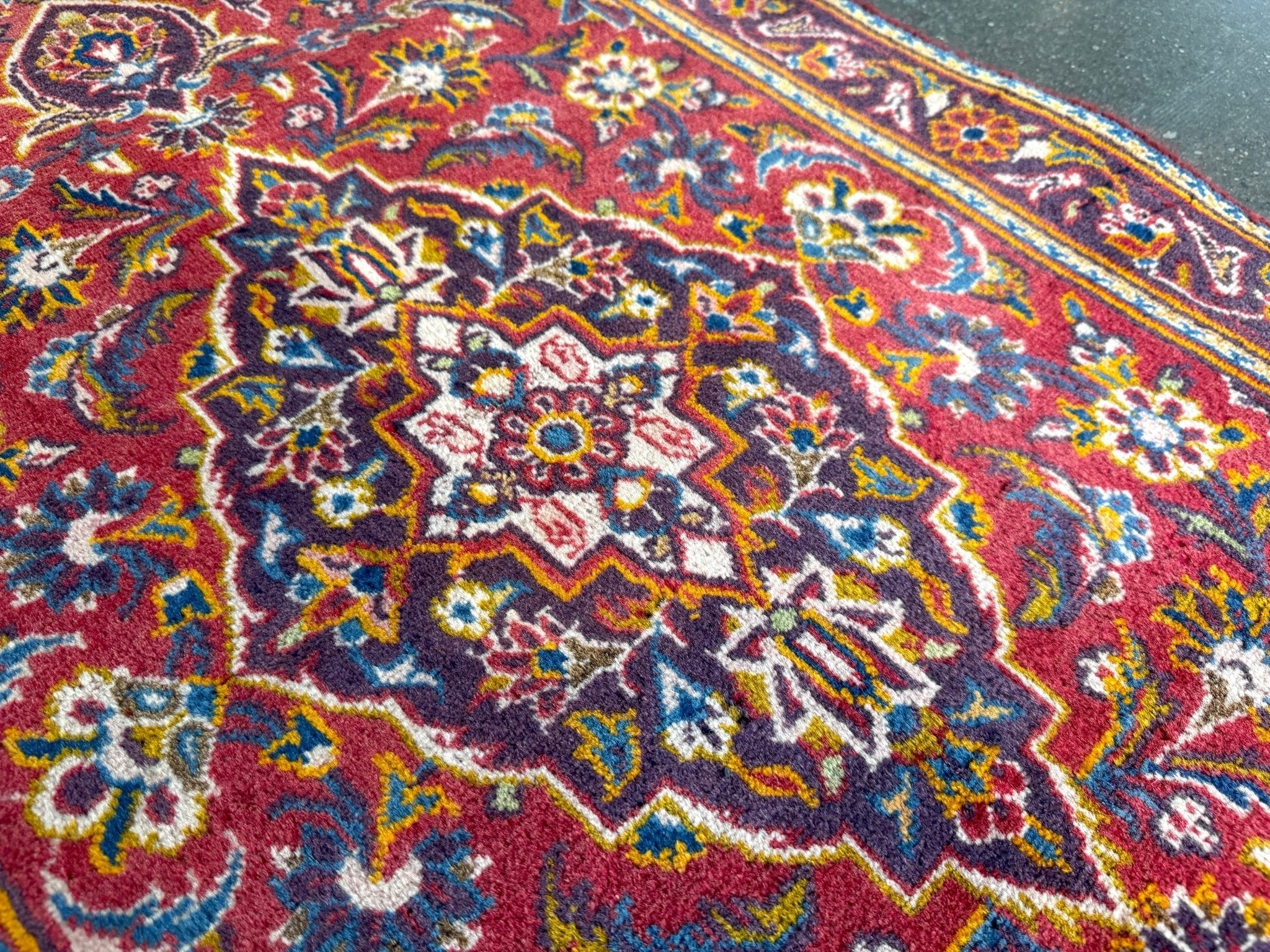 Persian Kashan rug close-up of central floral medallion on red background