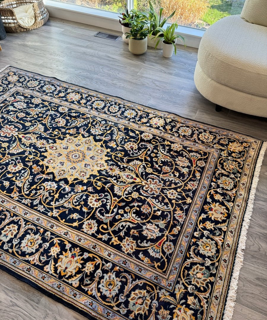 Navy Persian-style rug with cream floral vines and gold accents, fringed ends.