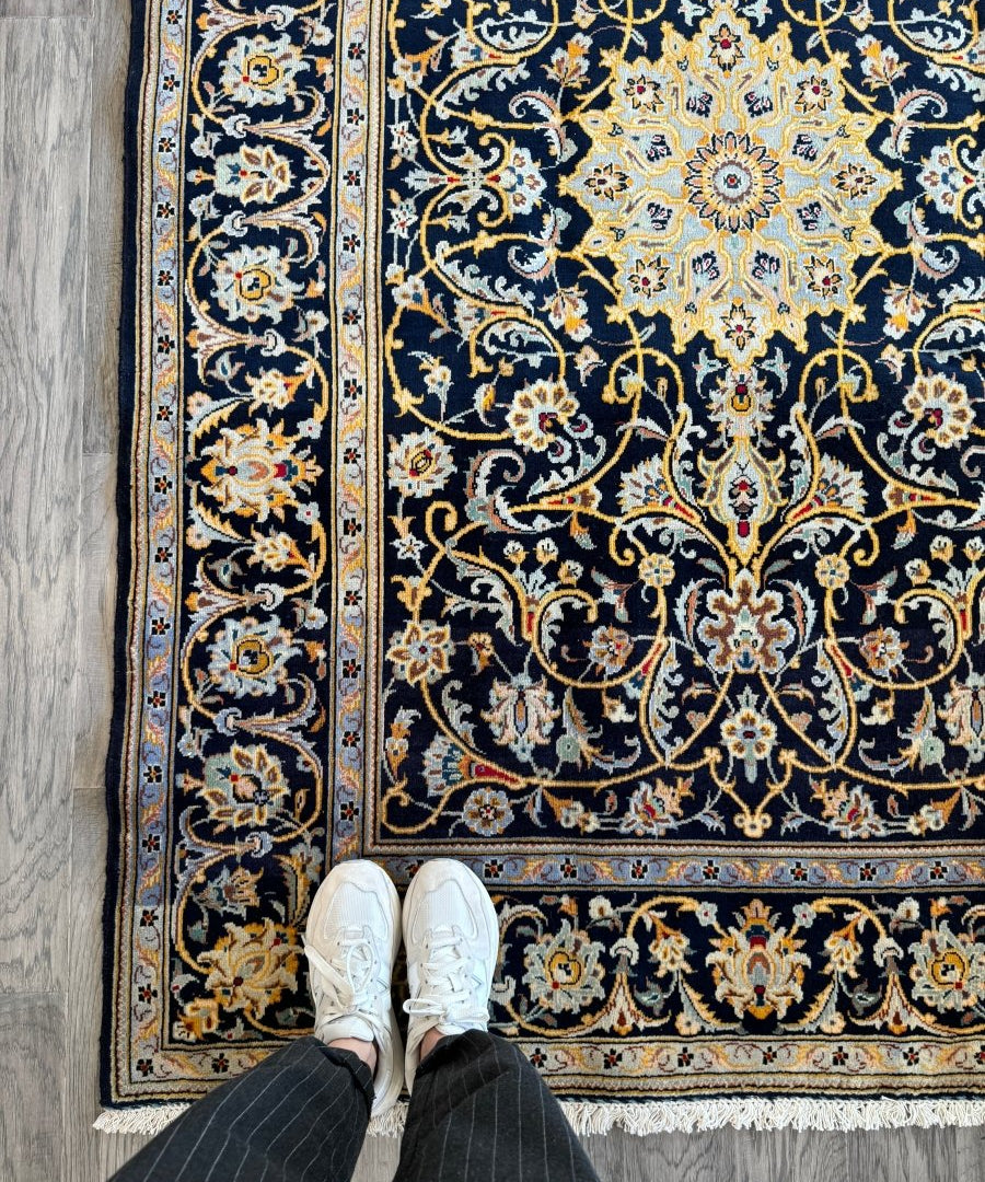 Persian-style area rug with navy field, cream medallion and ornate floral scroll border.