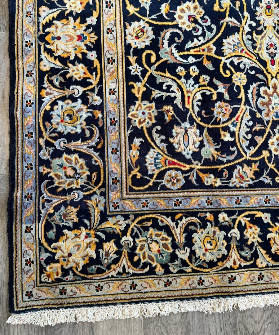 Close-up of navy Persian-style rug with cream, gold, and multicolor floral pattern.