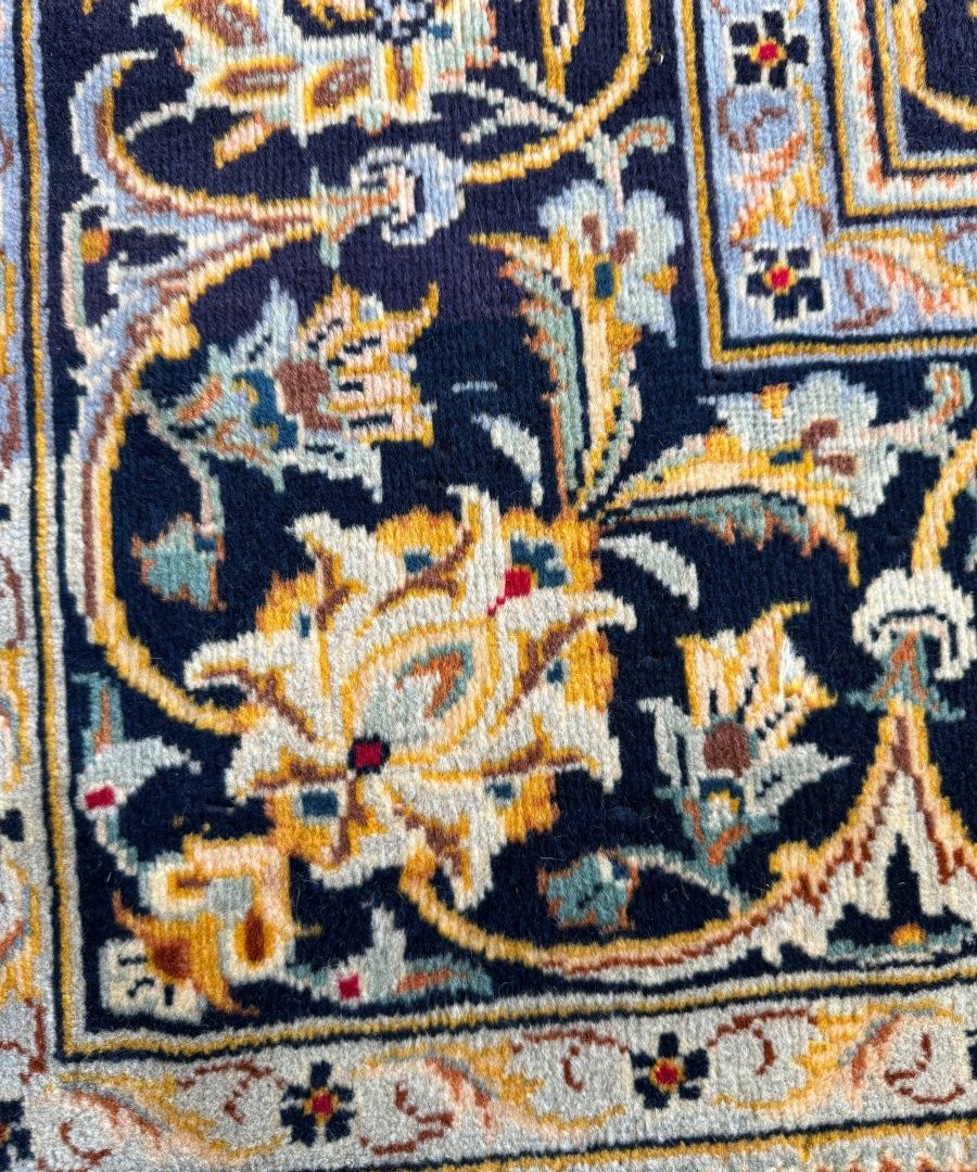 Detail view of Persian-style rug showing dense floral motifs on dark blue ground.