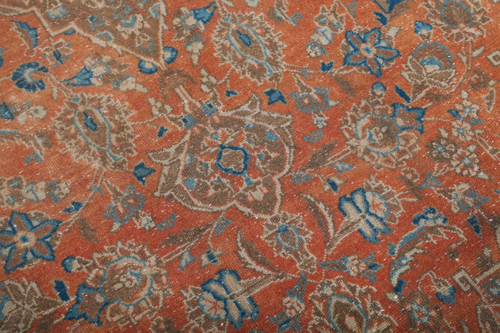 Orange rug surface with scrolling blue vines and ornate floral pattern