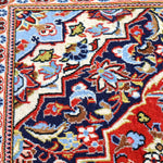 Persian Kashan rug close-up: cream field with navy and red floral motifs