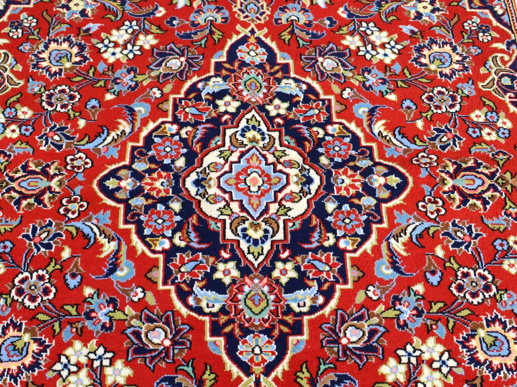 Persian Kashan rug full view: red ground with navy accents and multicolor floral pattern