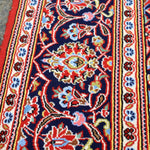 Persian Kashan rug detail: red and cream medallion on dark blue ground, ornate border
