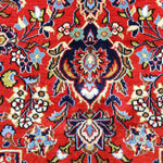 Close-up of rug medallion with red backdrop, blue accents, and cream floral highlights