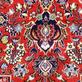 Close-up of rug medallion with red backdrop, blue accents, and cream floral highlights