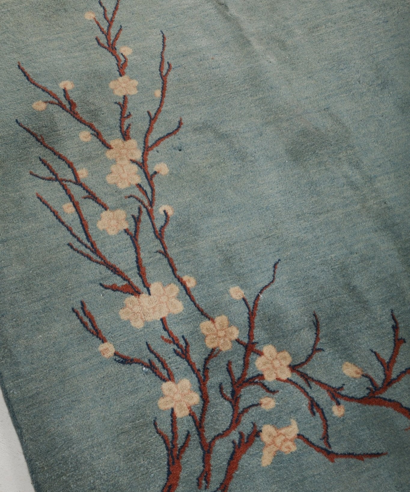 Light blue rug panel with red-orange branch and cream blossoms motif near center