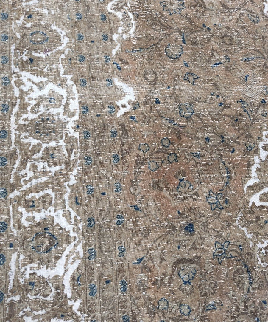 Kashan-style rug detail with white distressed floral shapes on beige and scattered blue dots