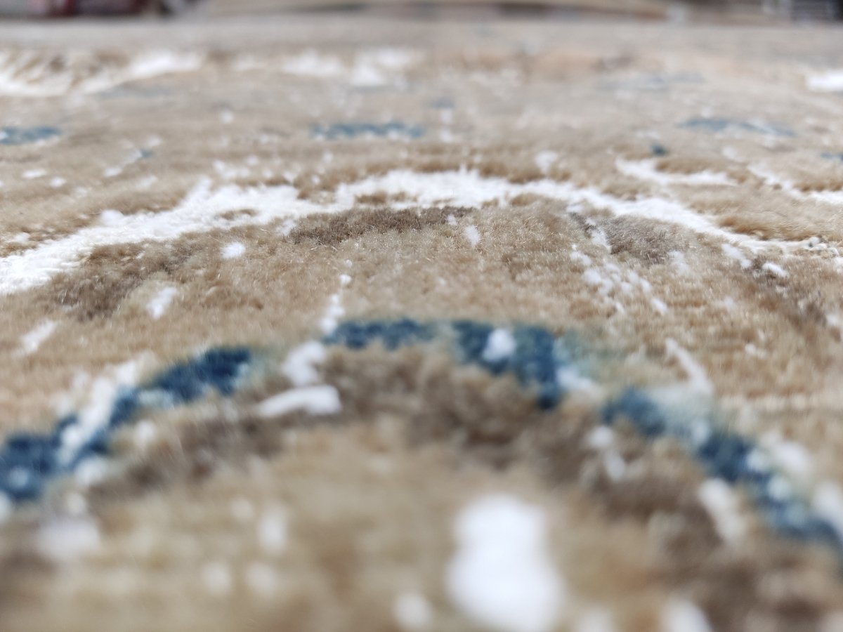 Close-up of Kashan-style rug texture; beige fibers with white wear and small blue flecks