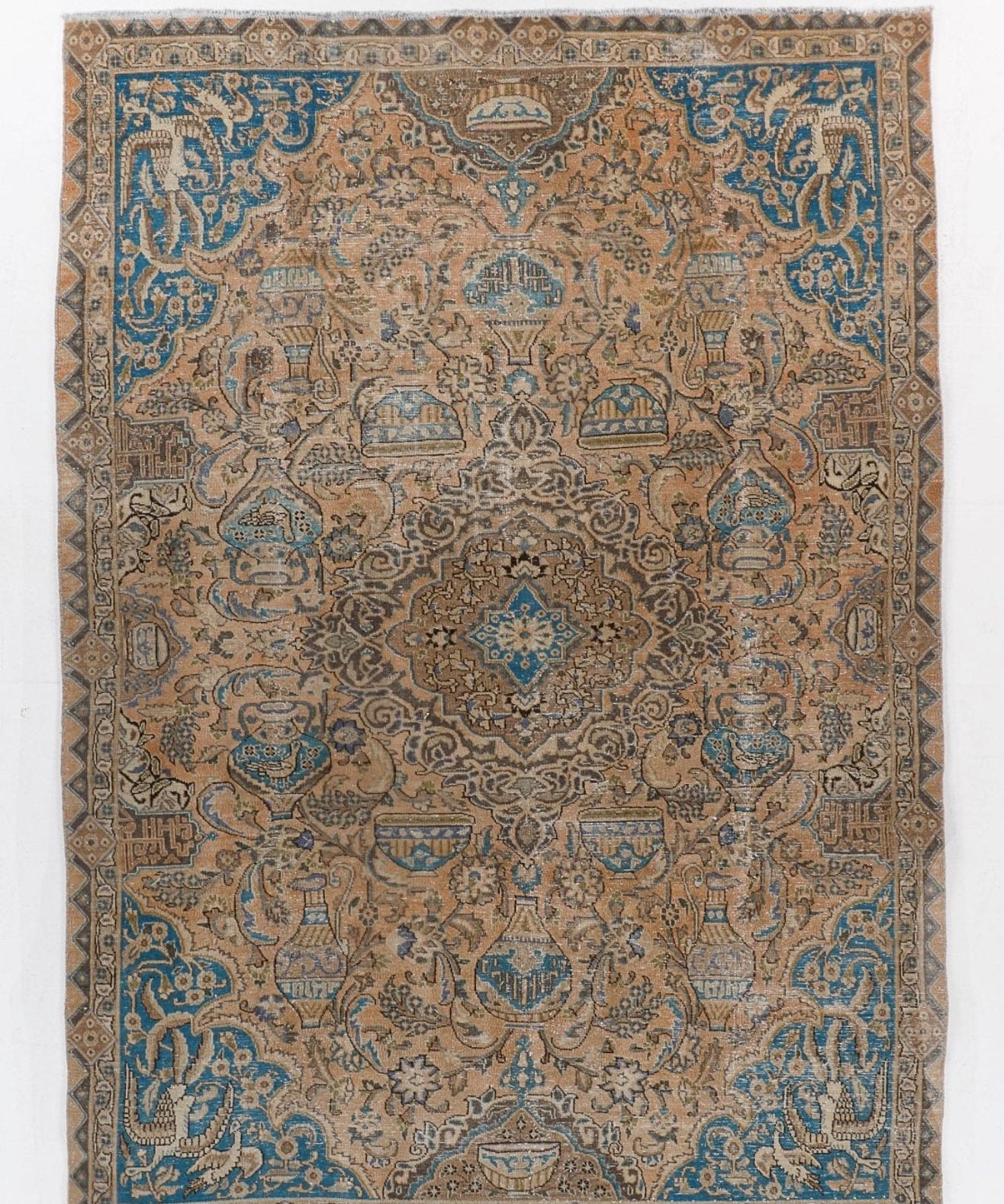 Persian rug with central medallion and blue patterns on tan ground
