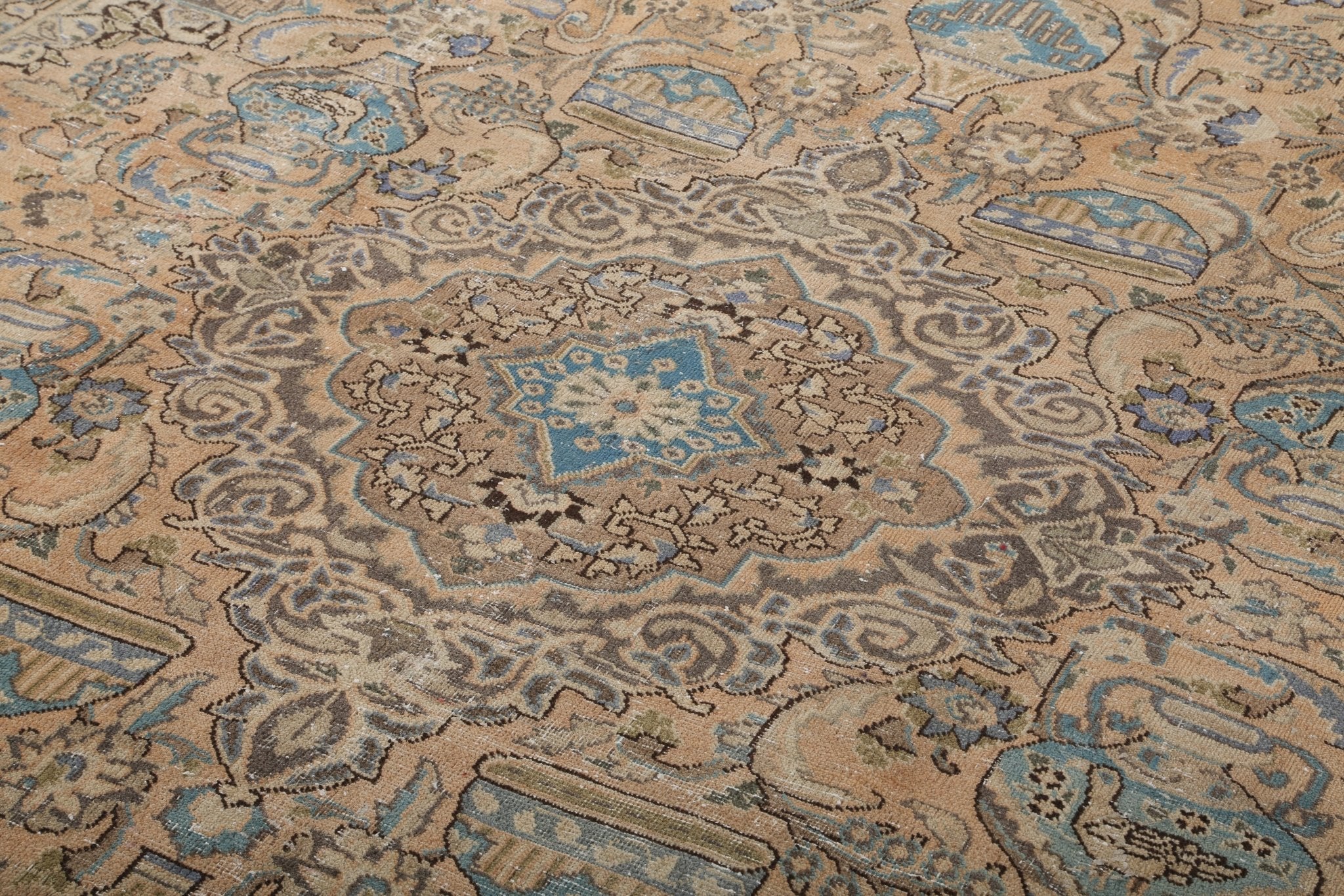 Persian Kashmar rug detail: beige ground with blue accents and repeating ornamental rosettes