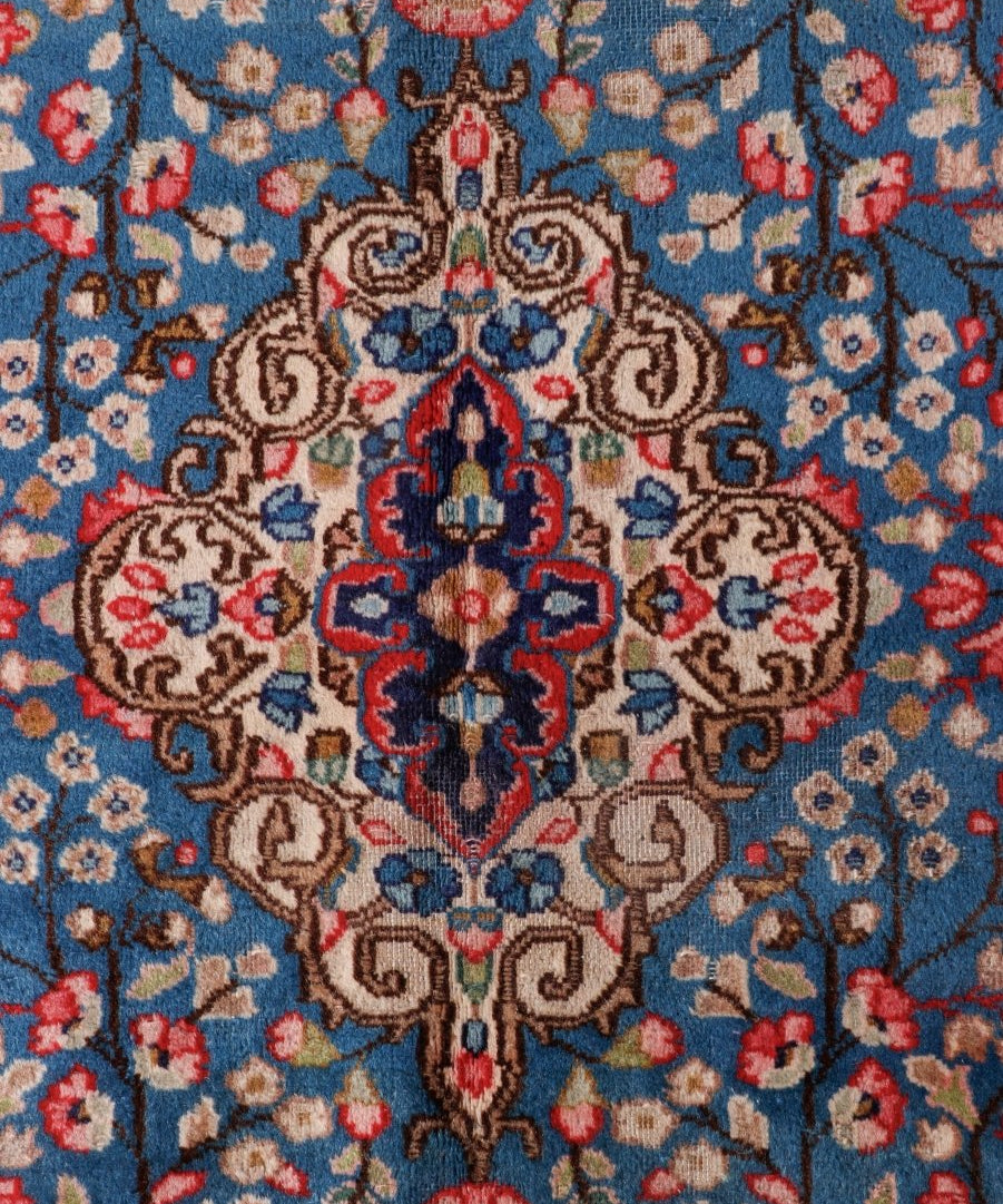 Close-up of Persian-style rug medallion in blue with red, cream, and tan details