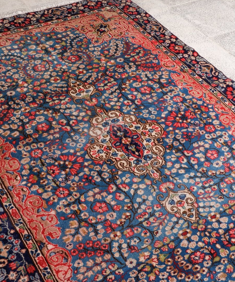 Persian-style rug corner with dense blue floral motifs and red decorative border