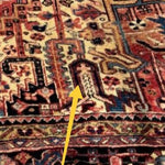 Persian Heriz-style rug close-up showing a cross-like motif on the patterned field