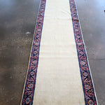 Cream Persian-style runner rug with dark blue floral border and red accents