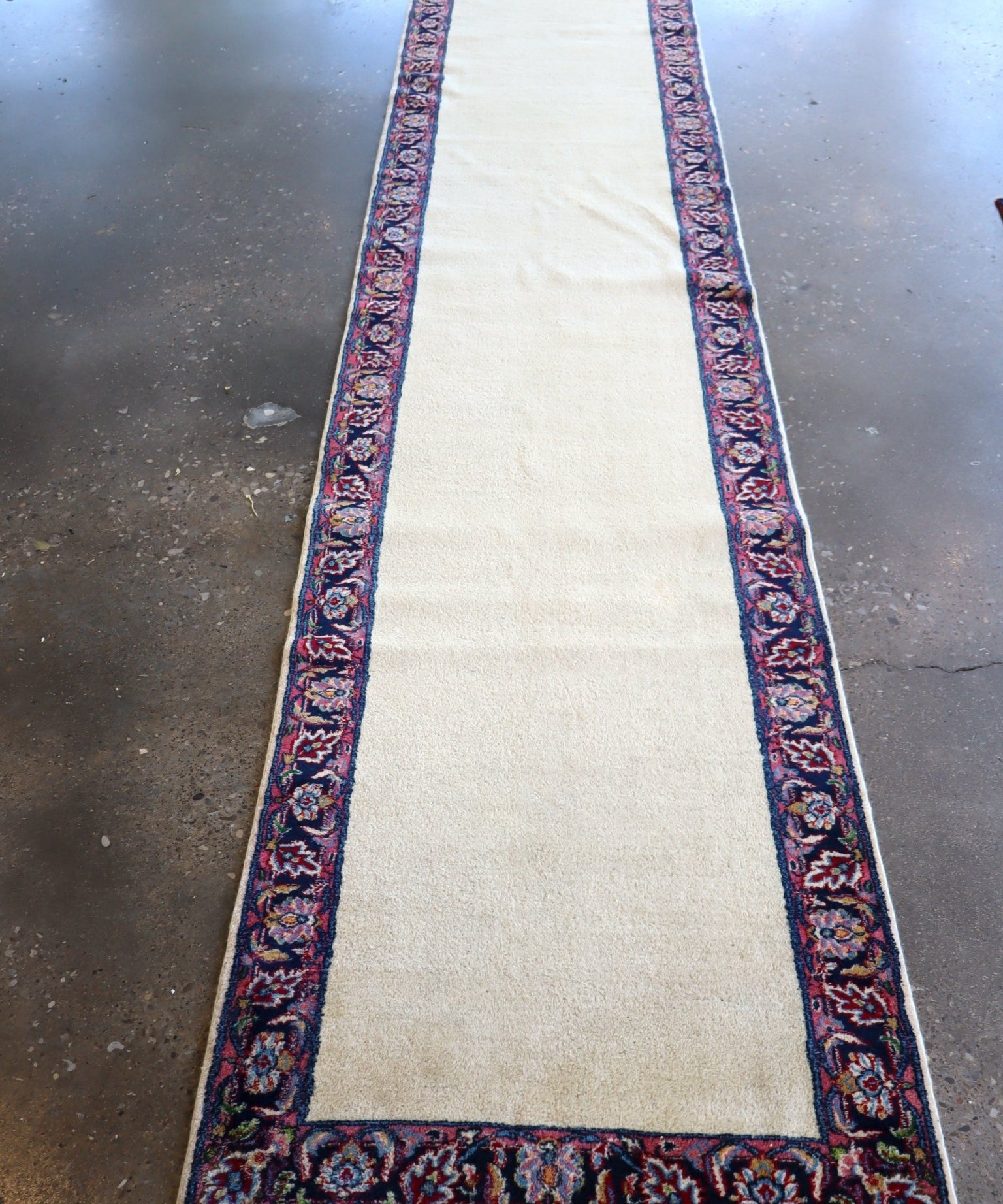 Cream Persian-style runner rug with dark blue floral border and red accents