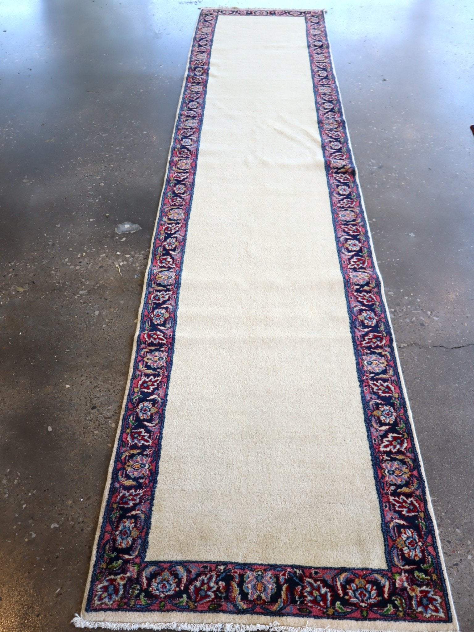 Cream Persian-style runner rug with dark blue floral border and red accents