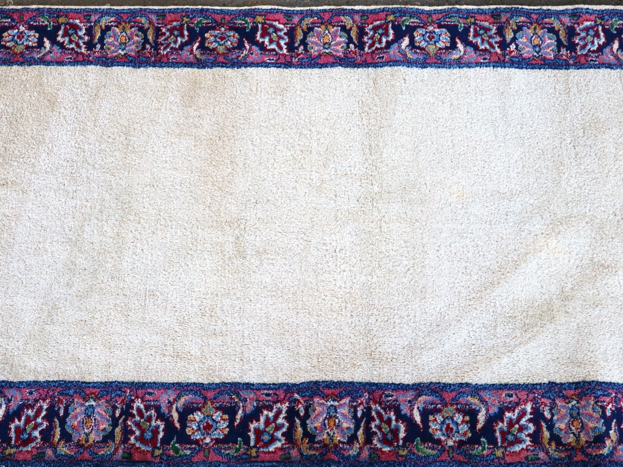 Cream rug field with navy border and repeating blue-red medallion band
