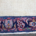 Rug border strip in navy with red and multicolor floral accents on off-white