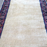 Off-white runner rug field with navy and red side border and floral medallions