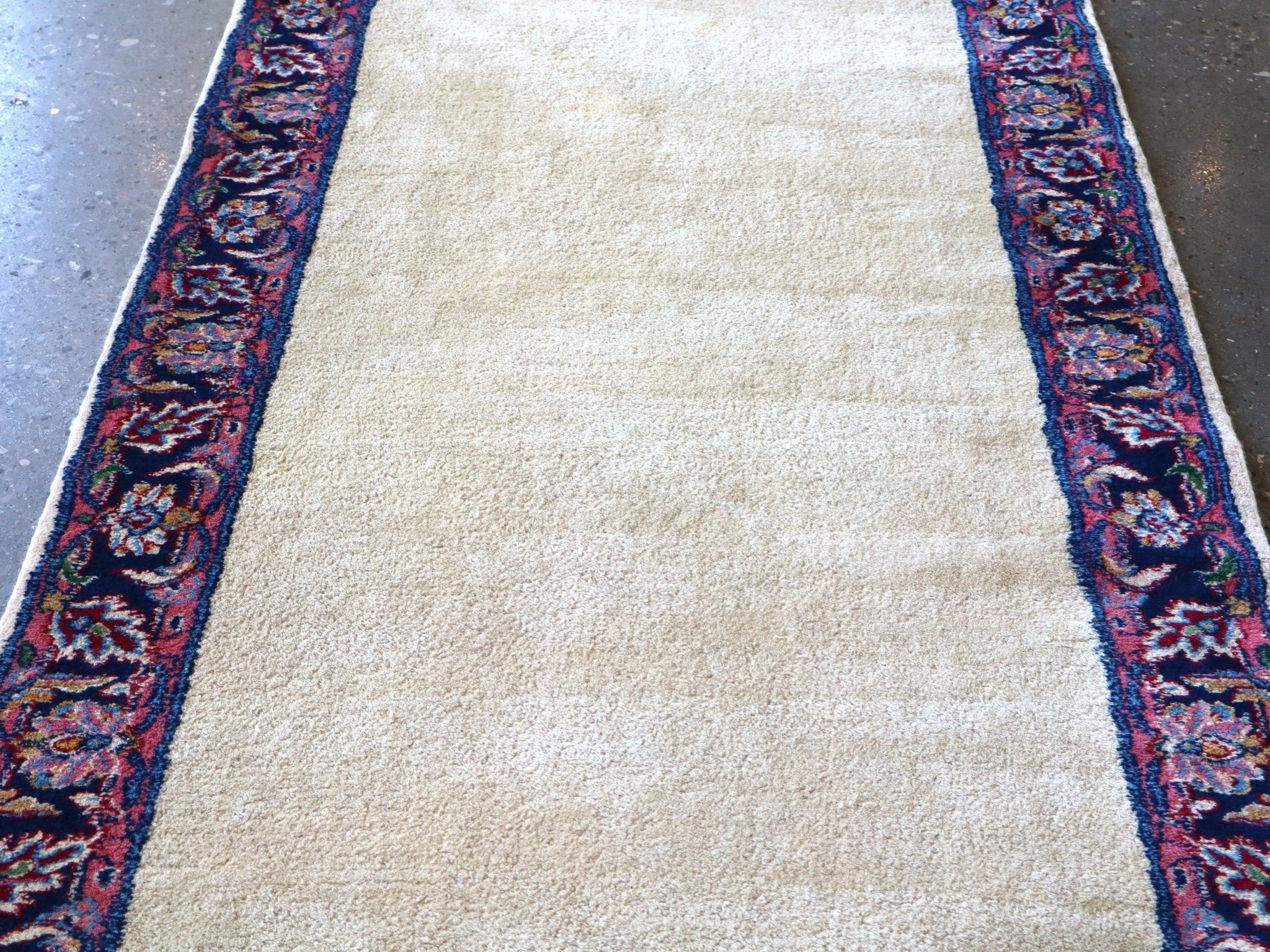 Off-white runner rug field with navy and red side border and floral medallions