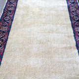 Off-white runner rug field with navy and red side border and floral medallions