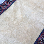 Off-white runner rug detail with navy-red border pattern along the edge