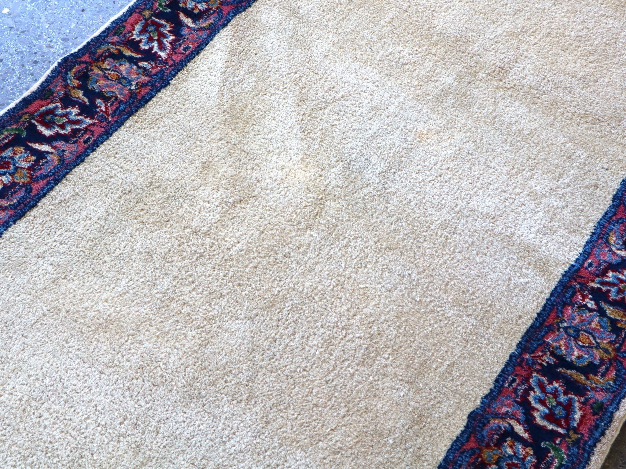 Off-white runner rug detail with navy-red border pattern along the edge