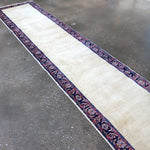 Long runner rug with off-white field and navy-red patterned border