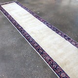 Long runner rug with off-white field and navy-red patterned border