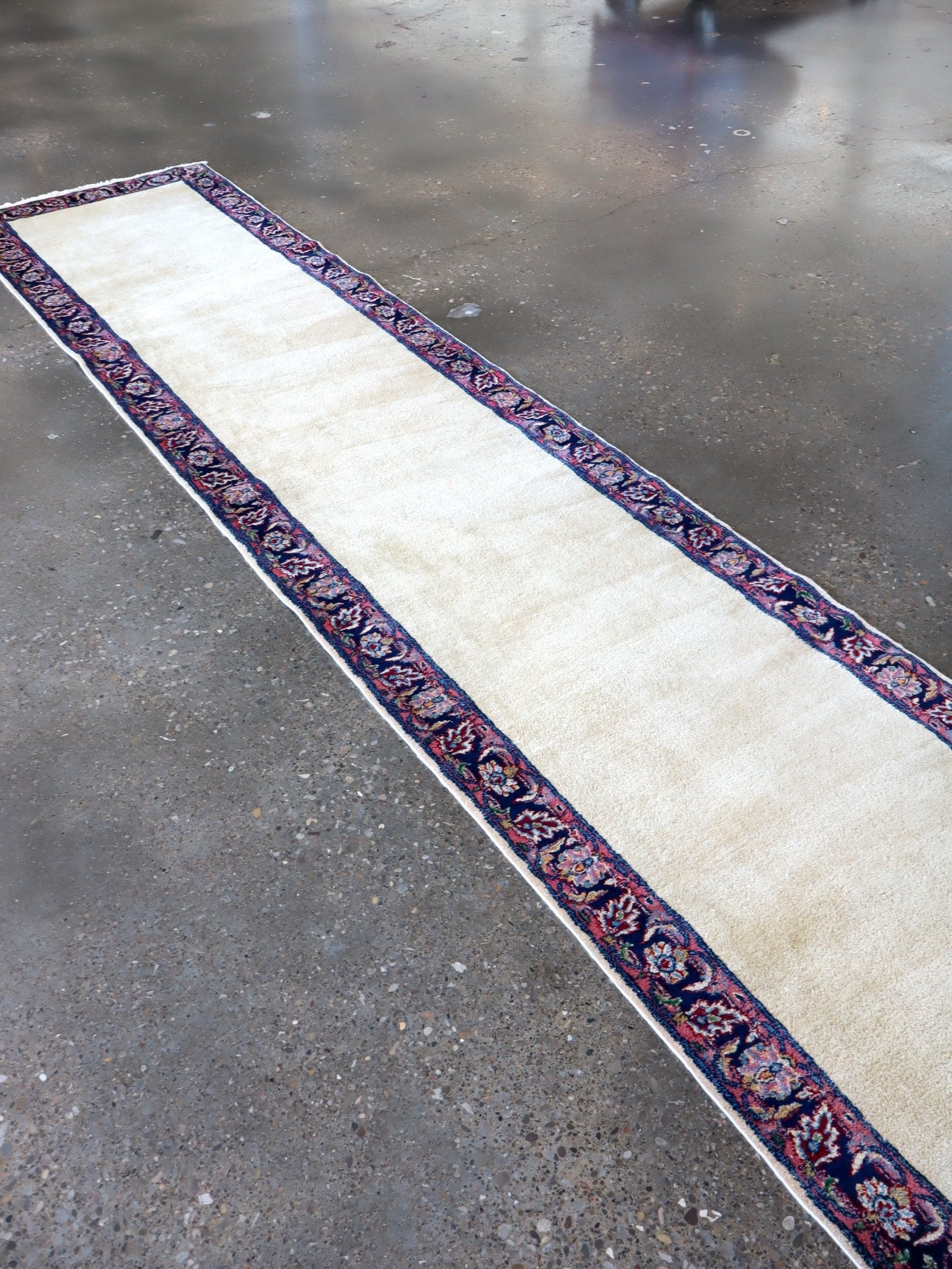 Long runner rug with off-white field and navy-red patterned border