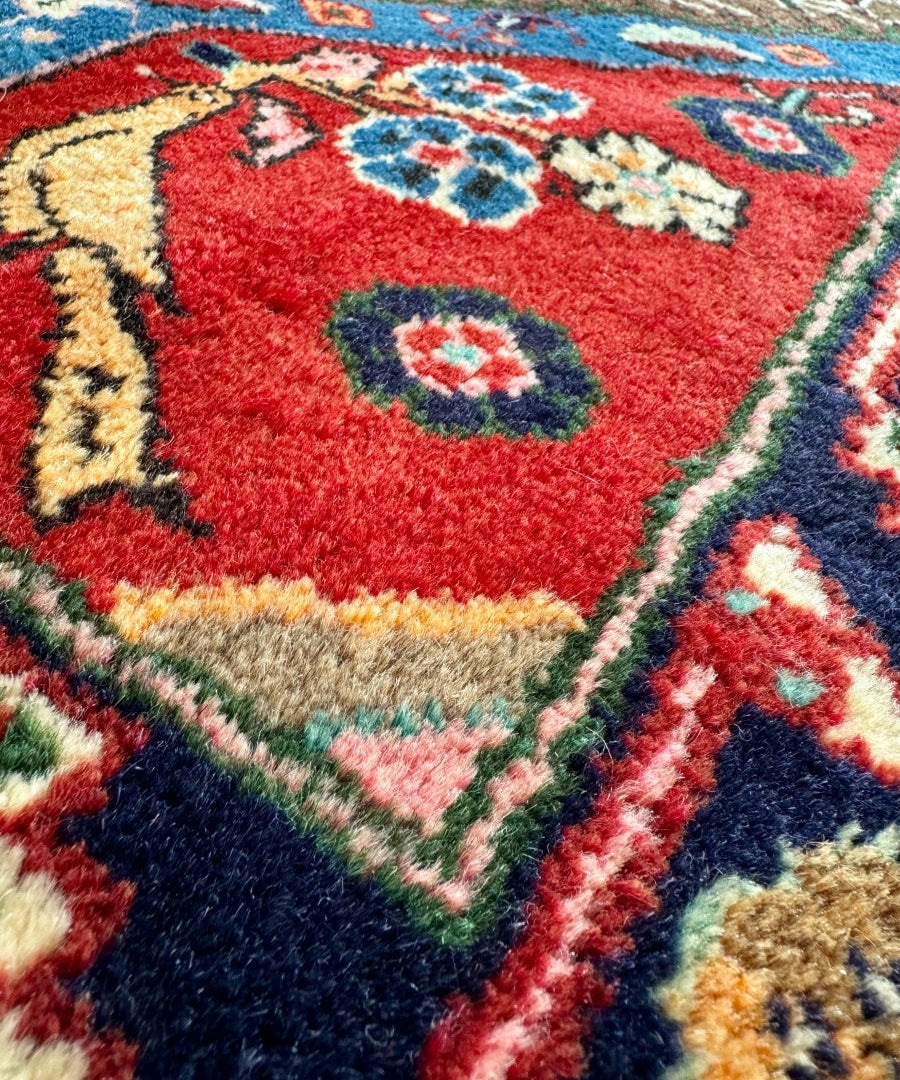 Koliai rug close-up with red field, teal accents, and dark blue edging.