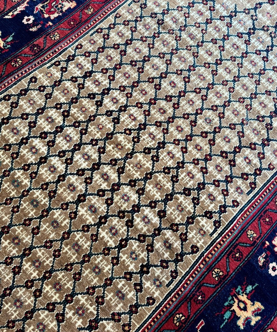 Persian Koliai rug close-up: cream field with dark navy linked lattice
