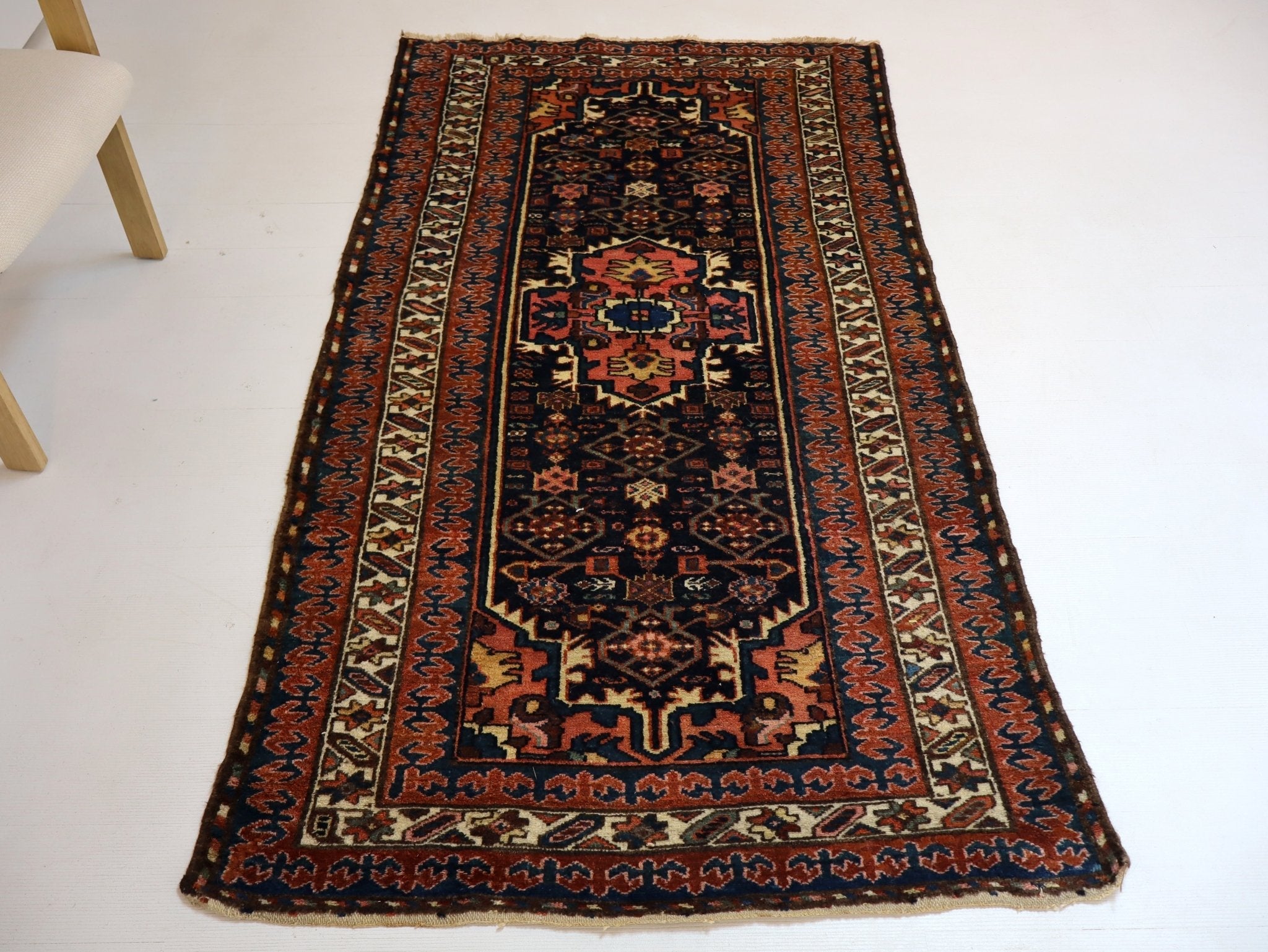 Persian Kurdi rug straight-on view with navy field, rust border, and medallion motif