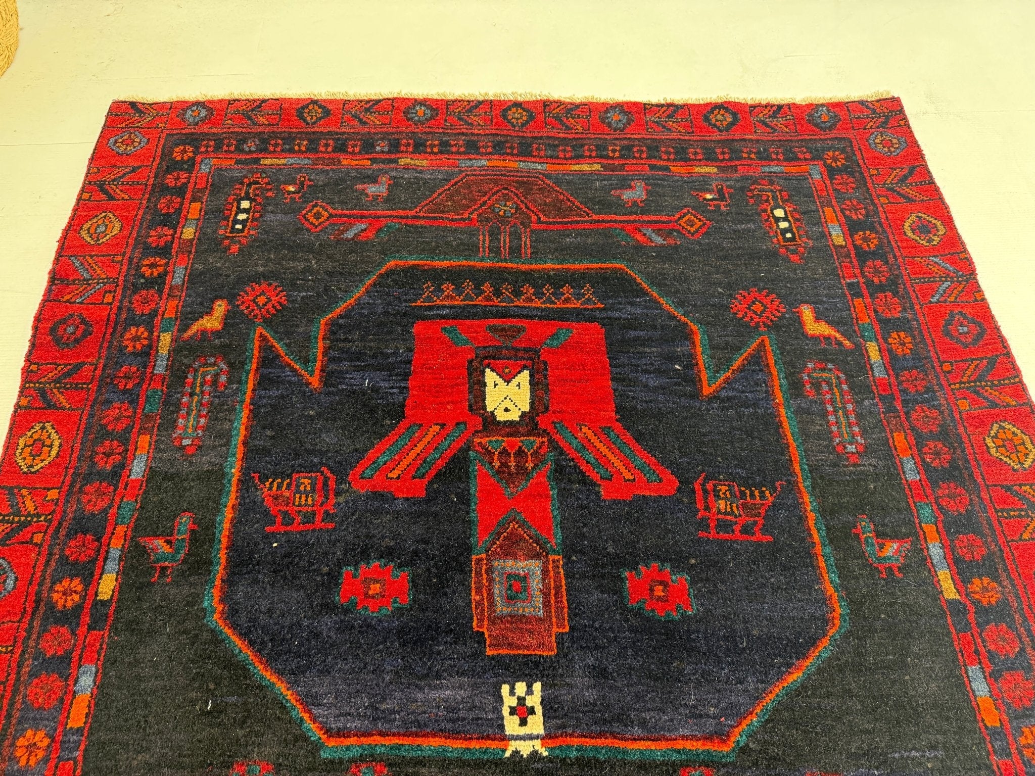 Kurdish Koliai rug center medallion, dark navy field with red surround and bird-like figure.